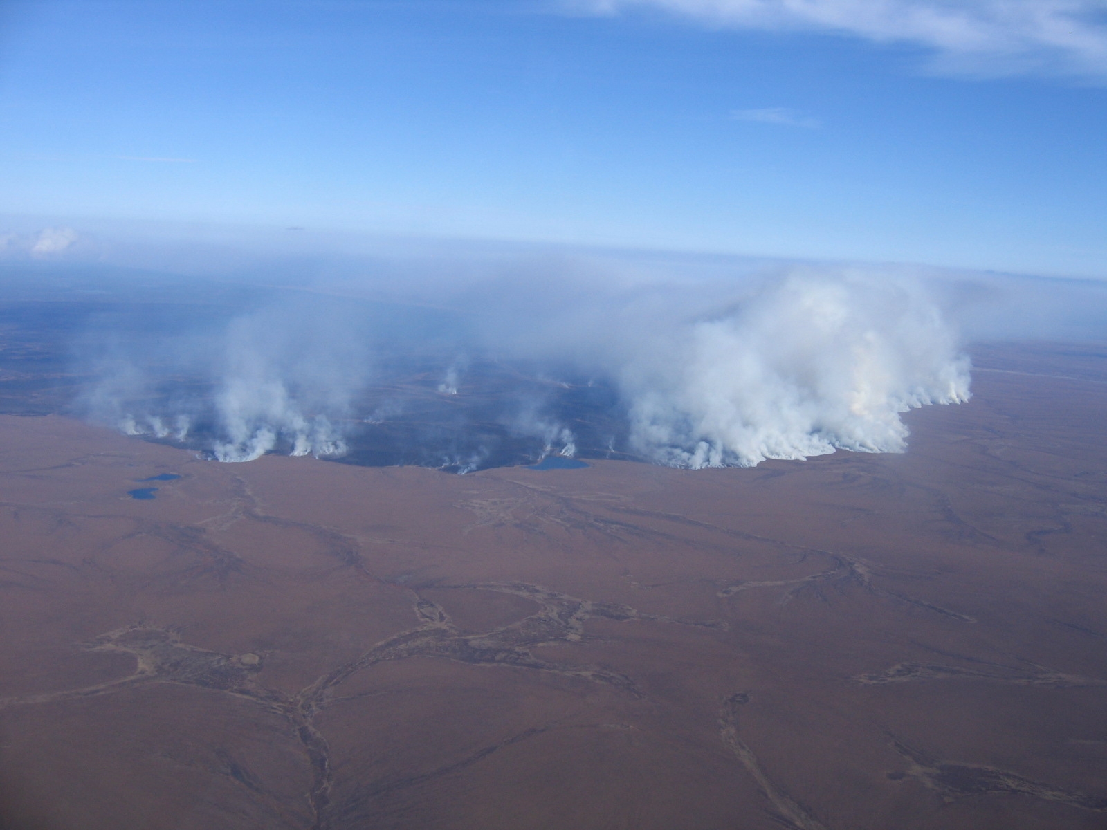 View from an airplane of the smoke and blackened land in the Anaktuvuk River area in Alaska due to a wildfire.