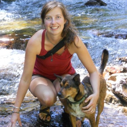 Portrait of Rebecca Fritz at a creek with a dog.