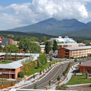 Northern Arizona University campus in the summer showing buildings in the foreground and the San Francisco Peaks in background.