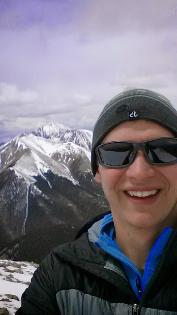 Portrait of graduate student Brian Howard with snow-covered mountains in the background.