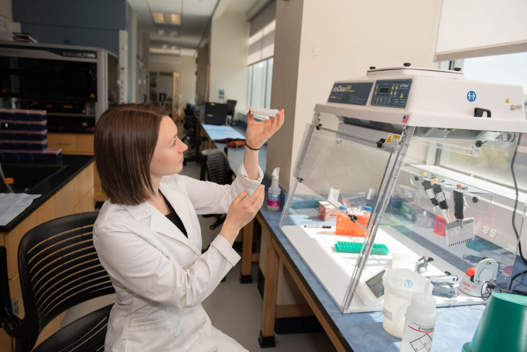 Lab scientist holds plate in molecular lab